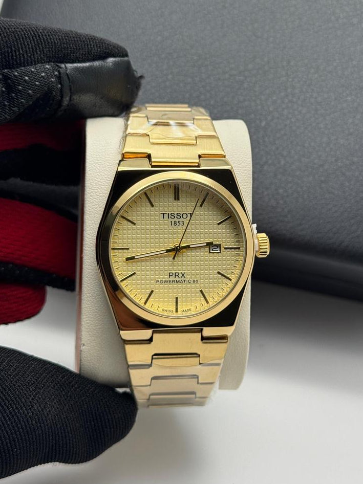 Gold wristwatch with Tissot logo on a white surface