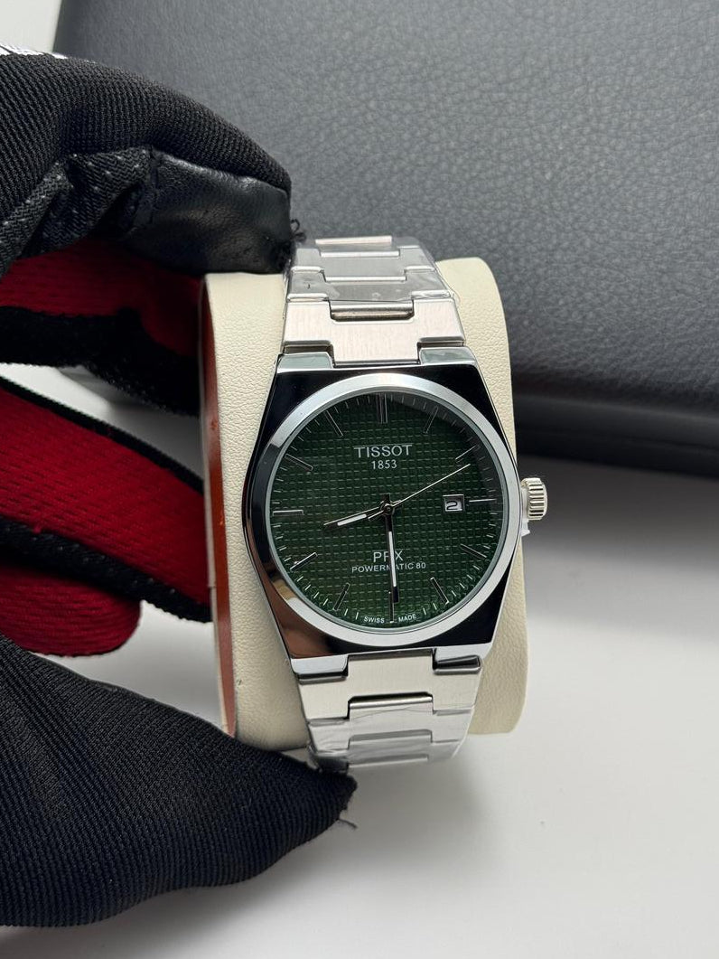 Silver Tissot watch with green face on a white surface