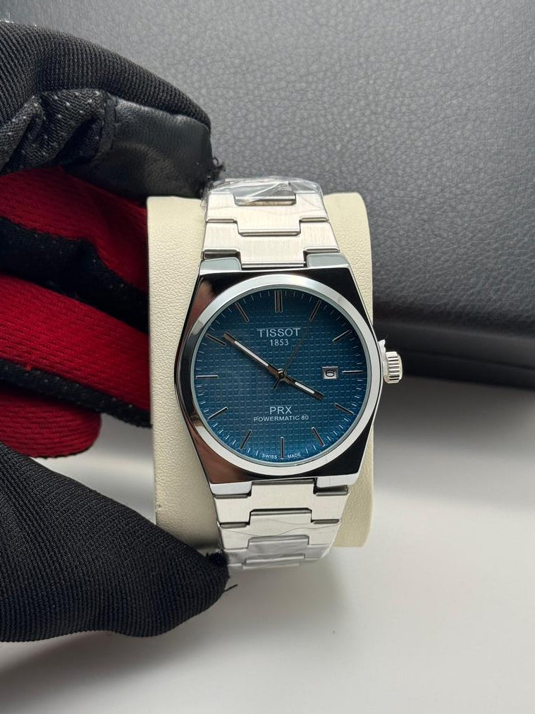 Silver Tissot watch with blue face on a gray surface