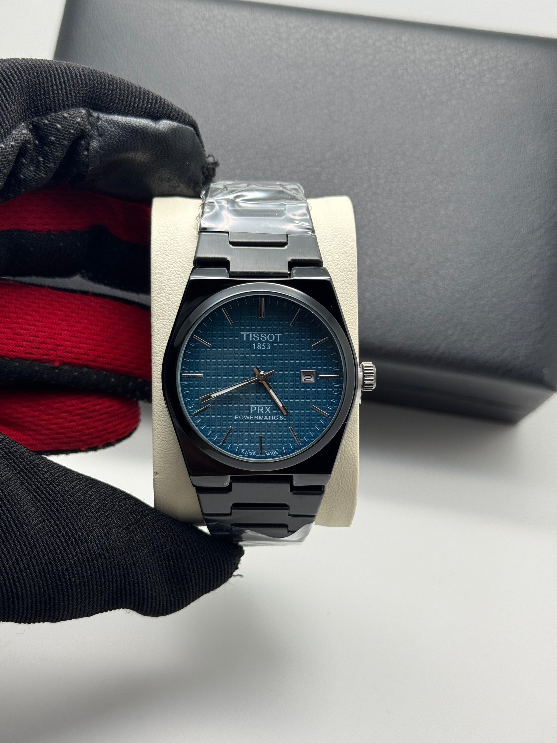 Tissot watch with blue face and black strap on a white surface