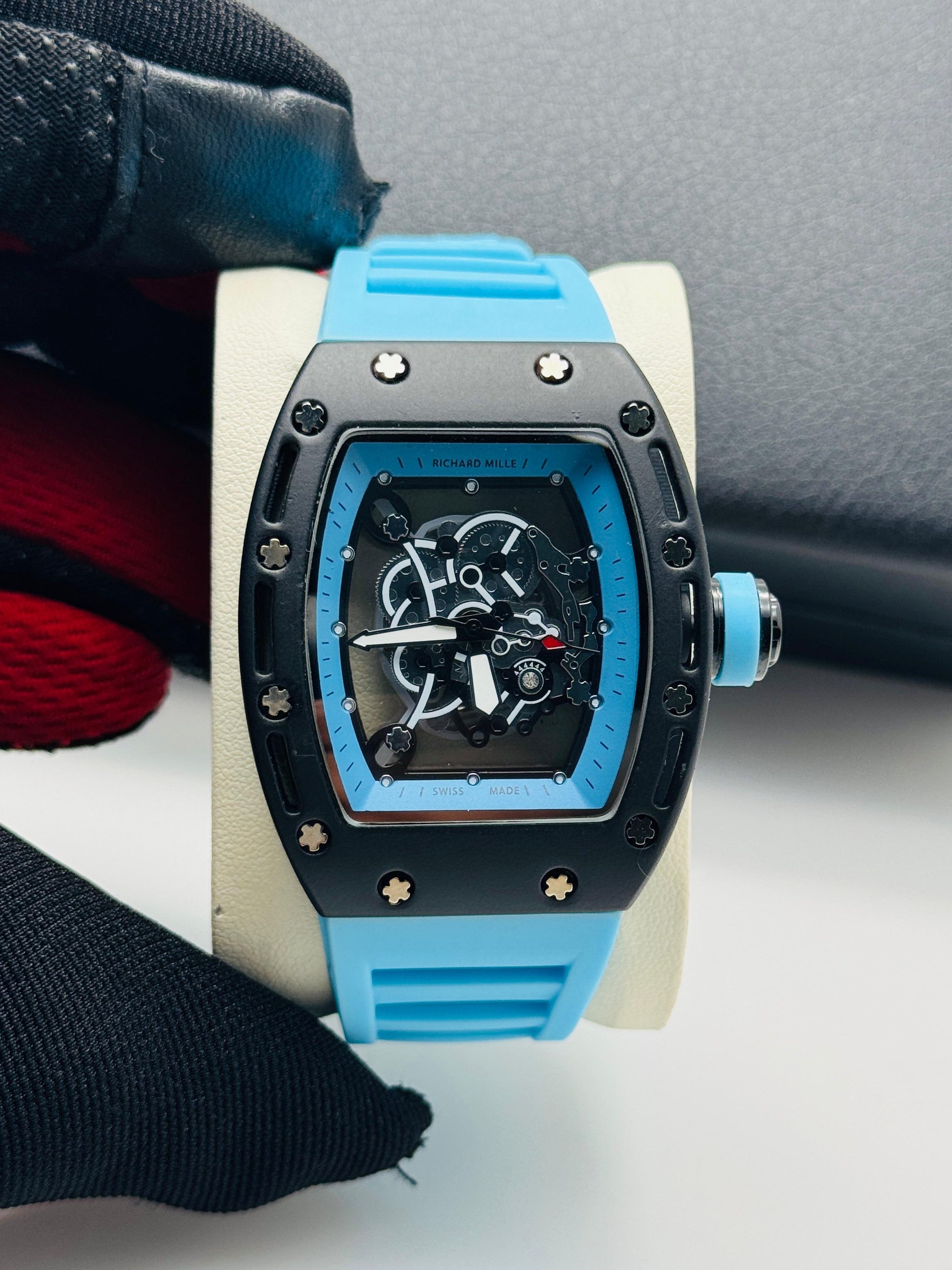 Blue and black watch on a white stand with a blurred background